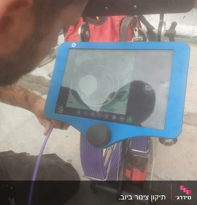 אדם משתמש במצלמת צנרת עם מסך תצוגה